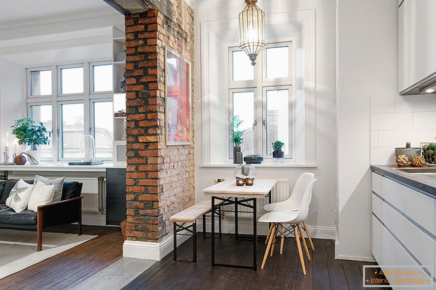 An arch of unplastered brickwork zonal divides the space into a living room and a kitchen