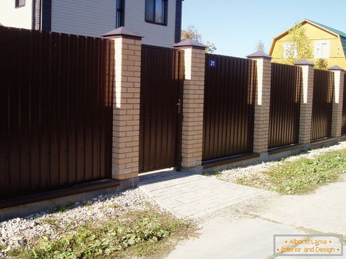 Modular fence is dark brown with a brick finish - a classic of the genre, if we talk about the design of suburban areas.