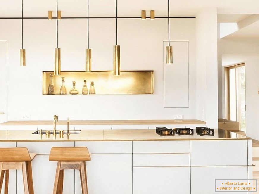 Golden decor elements in a white kitchen with wooden bar stools