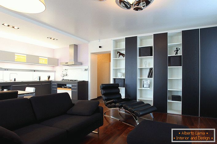 Black sofa, consisting of pillows, and a small ottoman are made to order for interior decoration in high-tech style.