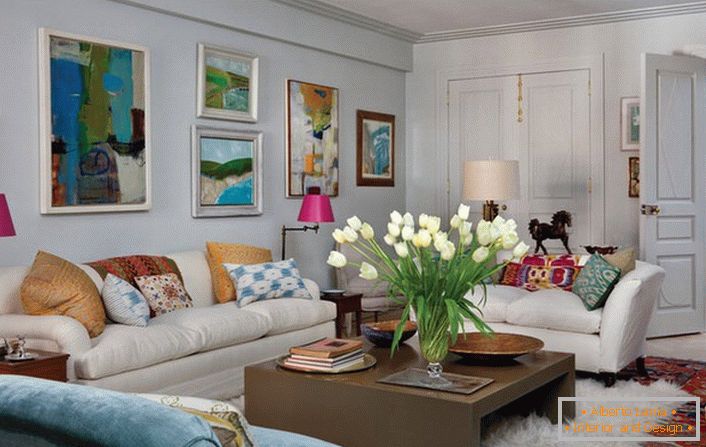Universal living room in eclectic style. A cozy room makes a lot of pillows and abstract, bright paintings that adorn the wall above the sofa.