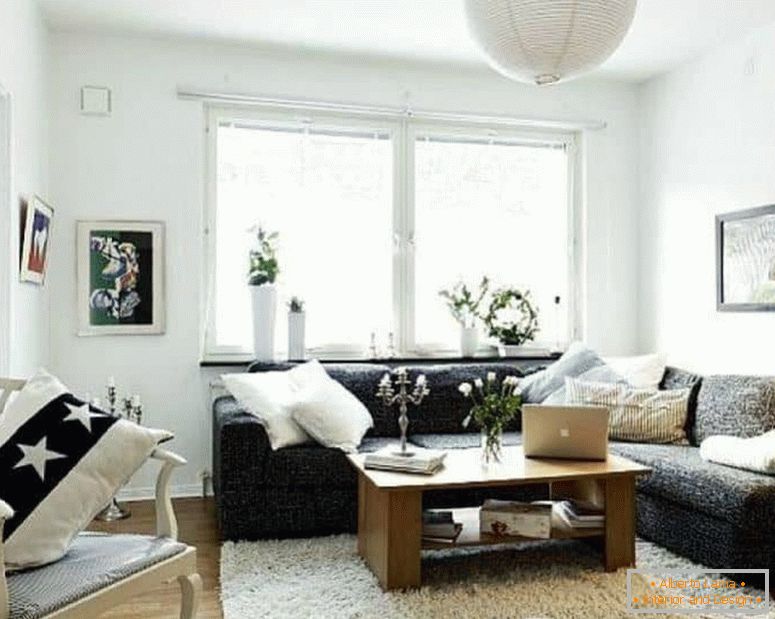 A small living room in white with a dark corner sofa and a window