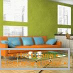 Orange sofa with blue pillows against the pistachio wall background