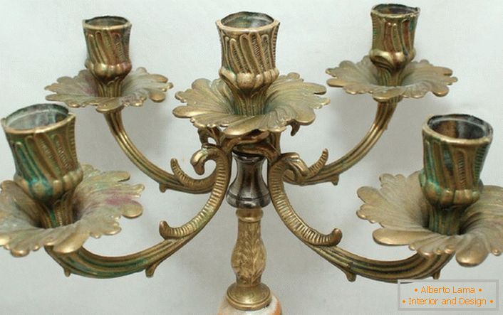 A stylish candelabrum made of brass with floral motifs harmoniously is written in the interior in the style of country.