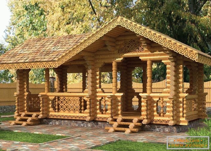 A fairy-tale gazebo in the style of a chalet is built of a light beam. To the gazebo lead the paths of granite tiles.