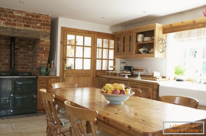 Spacious kitchen in country style. Wooden furniture and brick decoration over the stove give the style a natural and romantic.