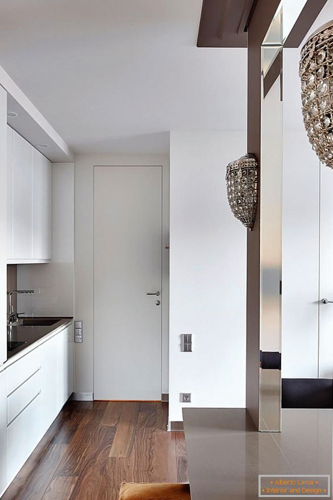 White kitchen furniture, white entrance door and beautiful wooden parquet