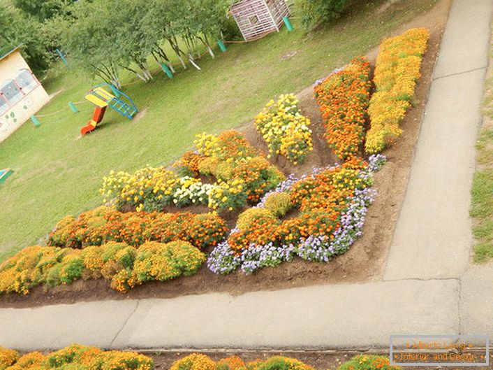 Modular flower garden in the form of a radiant sun looks harmoniously on the playground.