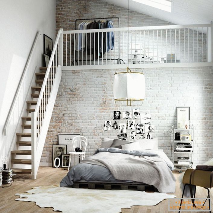 The bedroom in the Scandinavian style is functionally divided into two zones. A wooden staircase leads to the second floor, where there is a small dressing room on the bed.