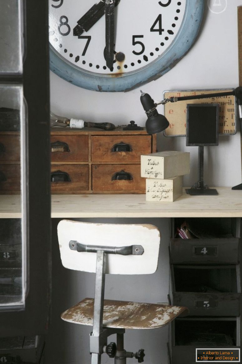 Old station clock above vintage desk with wooden organiser boxes and wooden swivel chair with peeling paint