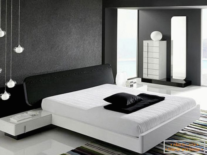 The wall at the head of the bed, decorated with a gray matte insert, in accordance with the style of hi-tech is in harmony with the glossy white floor.