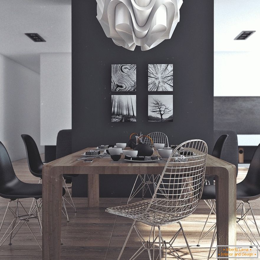 A wooden dining table, black chairs and original paintings on a black wall