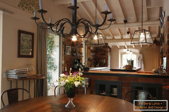 The dining and kitchen area is decorated in a country style. What is noteworthy is a chandelier above the table, which illuminates the space with the help of ordinary wax candles. Thin design idea, because in the room there is also a traditional lighting, working from the electrical network.