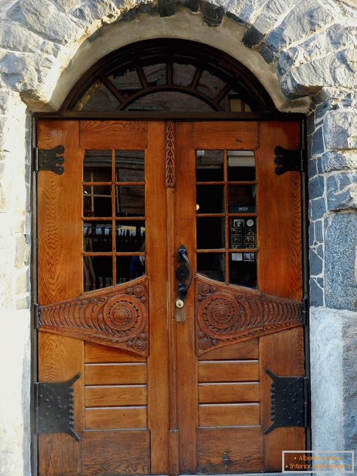 Doors in the Art Nouveau style decorate the front door of a country cottage with a facade made of natural stone. 