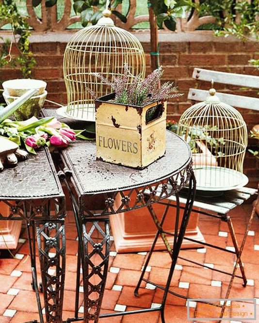 Forged table, boxes with flowers and cages for birds