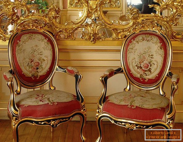 Openwork stucco of gold color on the mirror and chairs with red soft upholstery - bright representatives of the Baroque style.