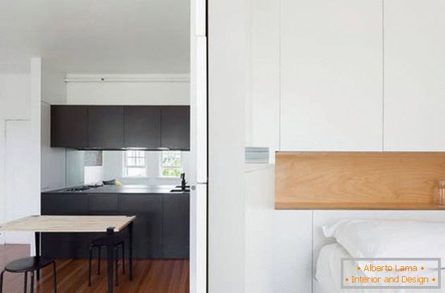 Modular wall in the interior of the apartment: a black kitchen and a snow-white bedroom