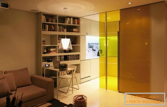 The kitchen is separated by a glass colored partition from the living room area