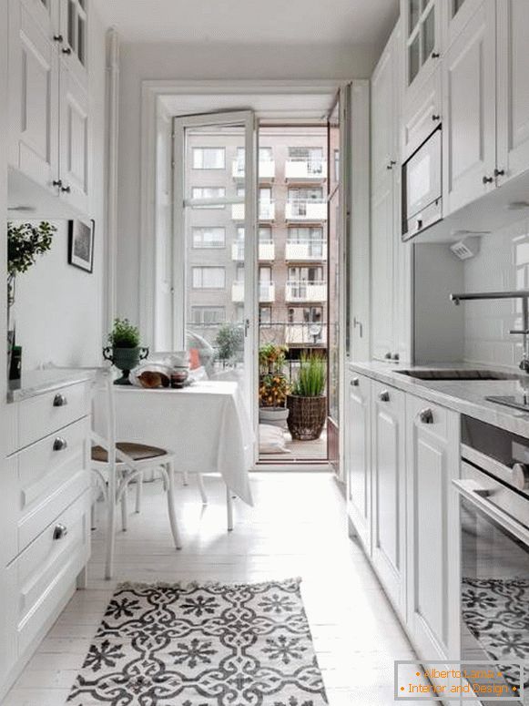 White kitchen in the interior - photo of a small kitchen with a balcony