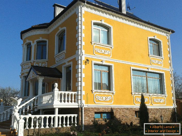 The facade of the building is decorated with stucco molding. A successful variant of decorating for a country mansion.