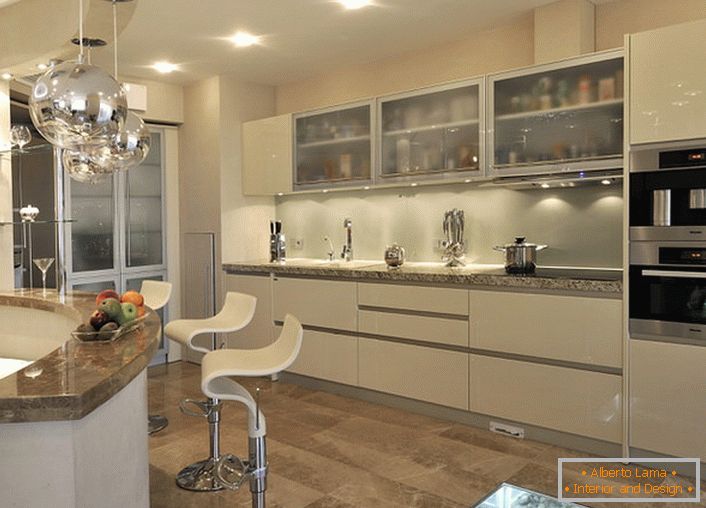 The kitchen sleeve is organized in a practical and elegant way. On one side is a kitchen set, and on the other - a bar counter, also used as a kitchen table.