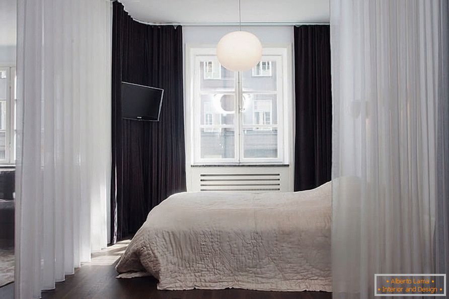 A bed with a curtain in a one-room apartment of 36 sq m