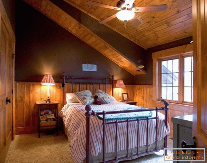 The guest bedroom on the attic floor in the style of the chalet is spacious and not superfluous with decorative elements.