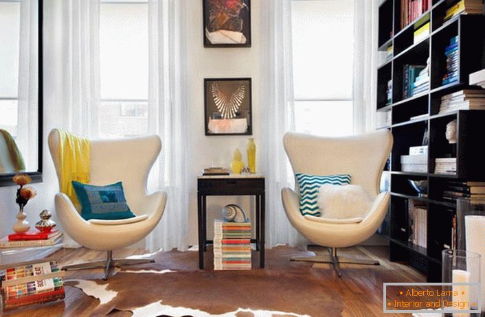 Exotic armchairs of unusual shape in the style of eclecticism. Shelves with many books in the corner for an avid reader. 