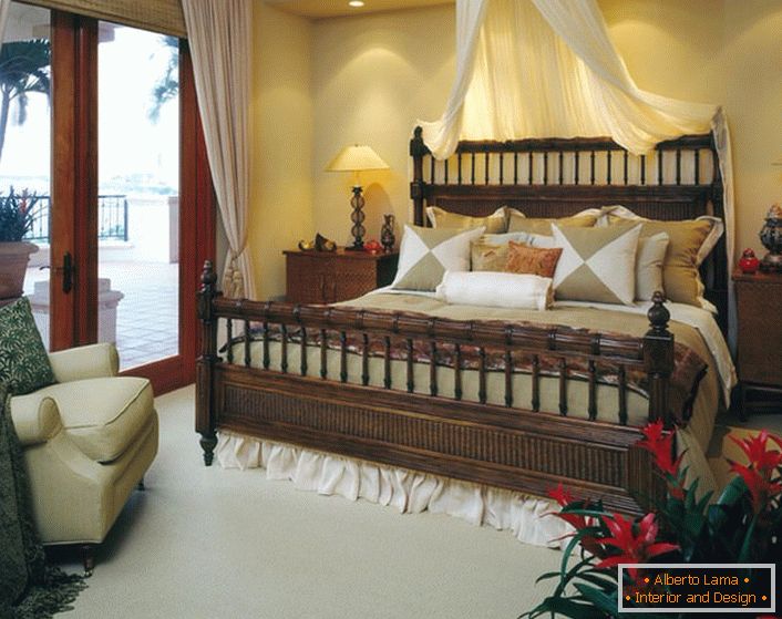 Luxurious bed in the bedroom in the style of eclecticism. Baldachin above the bed, light curtains on the doors leading to the veranda make the room cozy and romantic. 