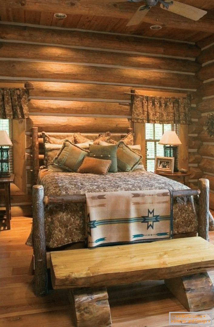 A classic example of a bedroom in a rustic style. Interesting bed of a rough, untreated log house. 