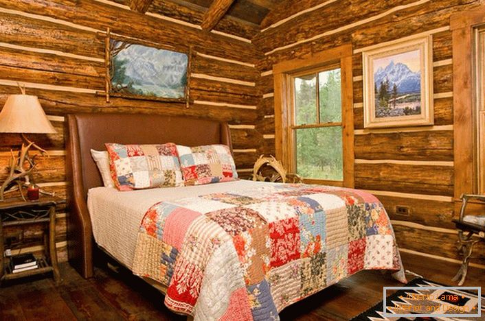 A bedroom in a rustic style in a hunting lodge. Noteworthy decoration of the walls with the help of a log house. 
