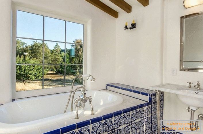 The snow-white bath is lined with bright blue tiles with a white pattern. Correctly selected ceramic tiles and wooden ceiling finish make the interior light and stylish.