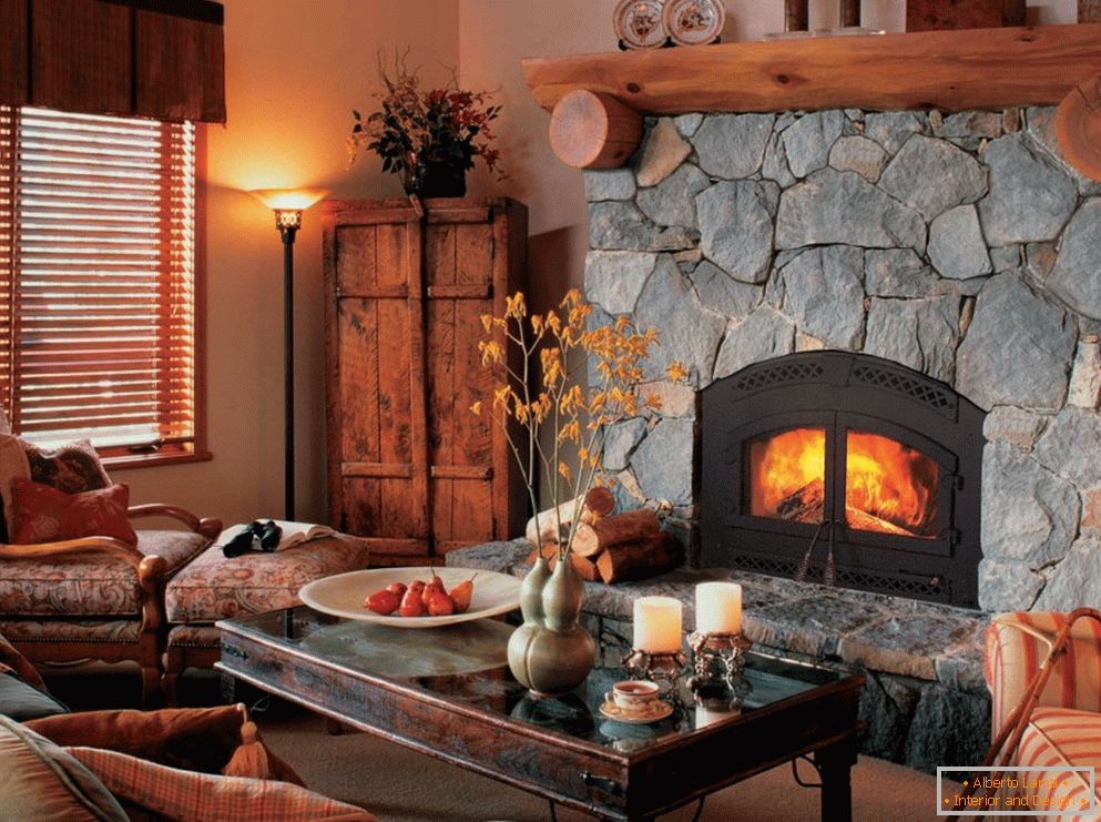 A bulky fireplace, decorated with a wooden frame, blends harmoniously into the guest room in the country style.