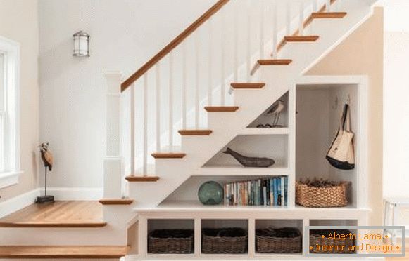 Design of a staircase in a private house with a cupboard under the steps