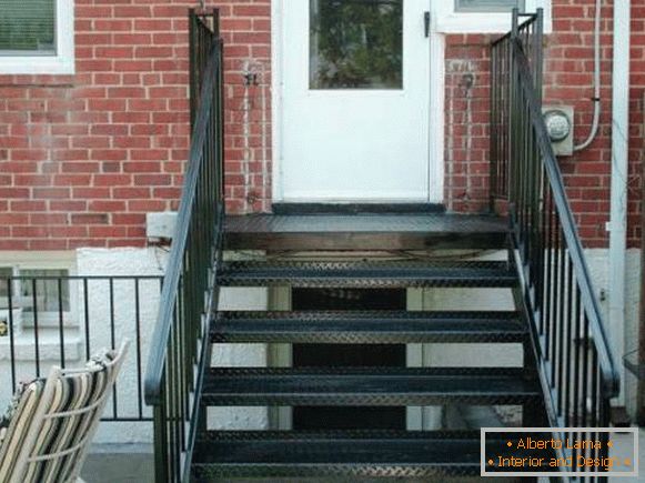 A small metal porch with a staircase to the brick house