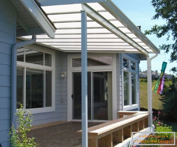 A small porch with a polycarbonate awning and a bench