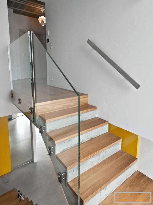 Concrete staircase with wooden steps and glass railing in a private house