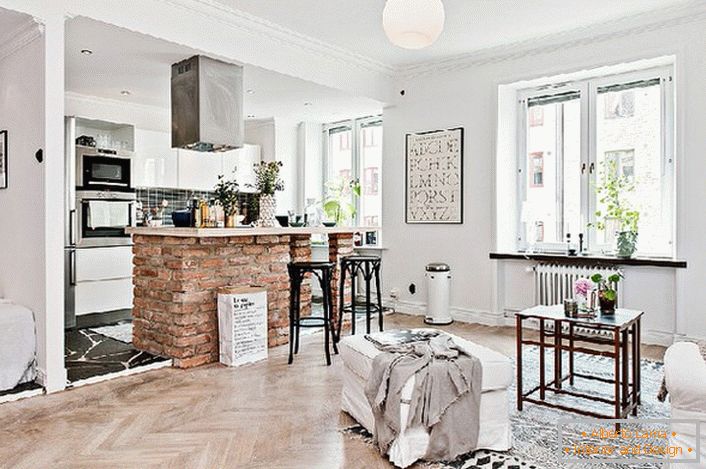 The studio apartment is decorated in Scandinavian style. The kitchen is separated from the living room by a bar counter made of bricks.
