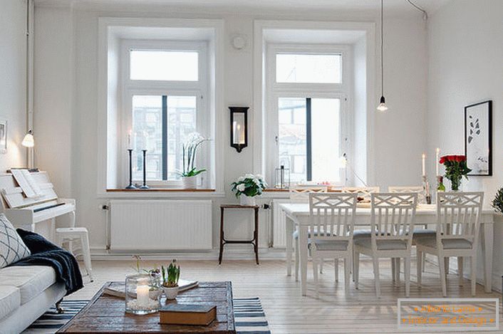 The stylish living room is divided into a seating area and a dining area. In accordance with the Scandinavian style, the walls of the room are decorated in white.