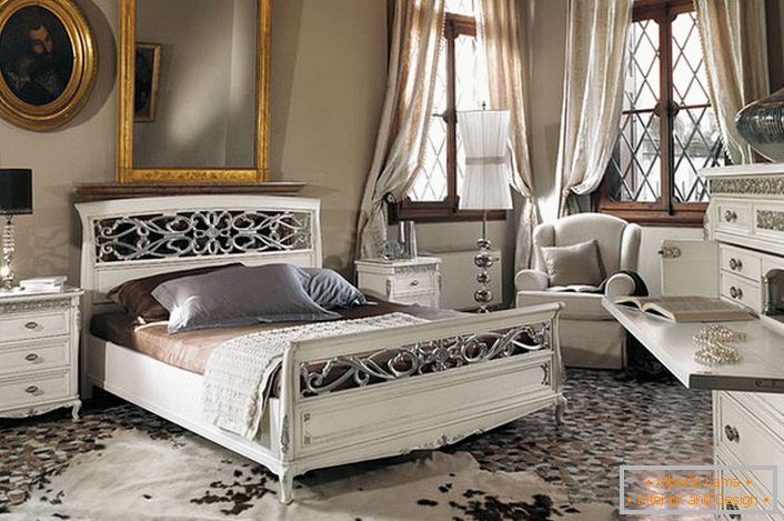The basic requirement of the baroque style is observed. In a spacious bedroom with high ceilings, white wooden furniture contrasts with the dark window frames.