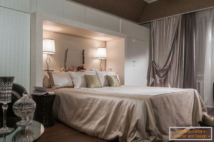 Noble bedroom interior in art-deco style. Attention is attracted to the functional cabinets of white color. Thanks to them, the room becomes quite spacious and bright.
