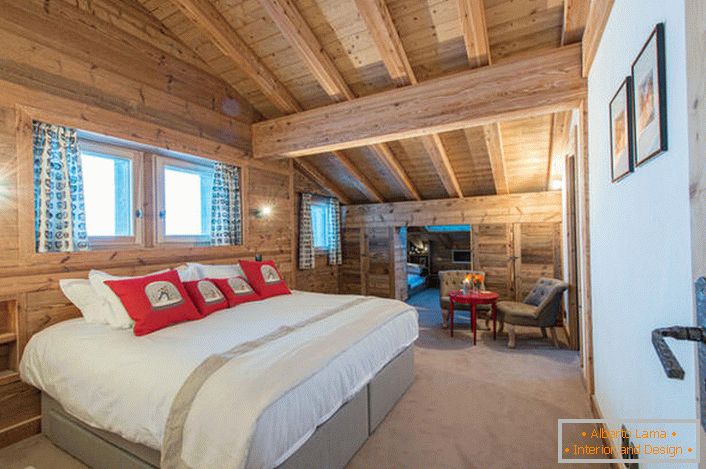 A spacious bedroom on the second floor of a country house from a wooden log house. В соответствии со стилем кантри искусственный свет в комнате приглушен. 
