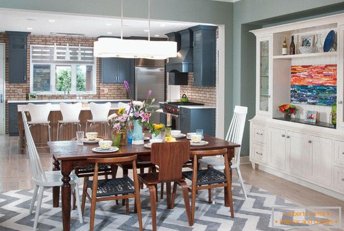 A large eclectic style kitchen is divided into a working and dining area. Furniture of white color is combined with elements of an interior of dark brown color.